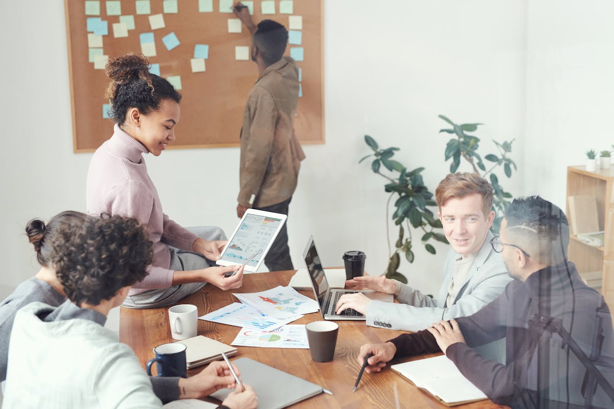 Small team of coworkers collaborating around a table with laptops and charts